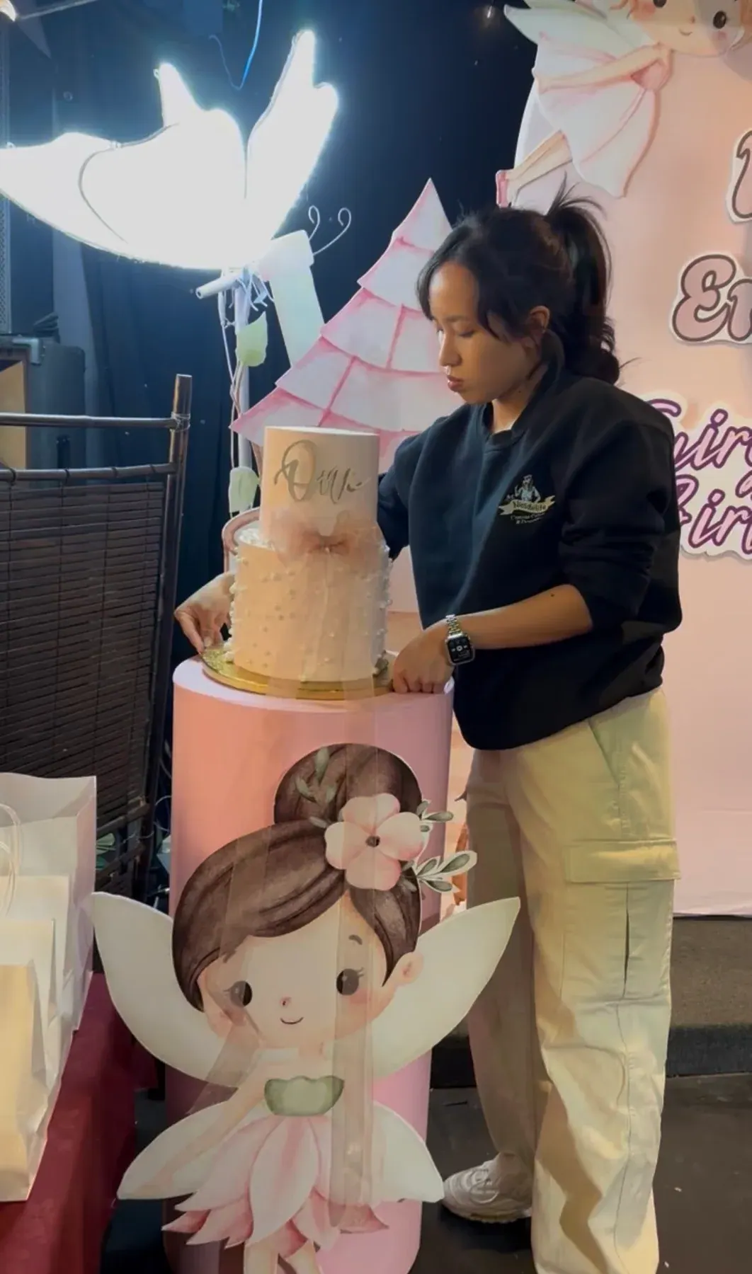Nicole beside a fairy-themed first-birthday cake and backdrop