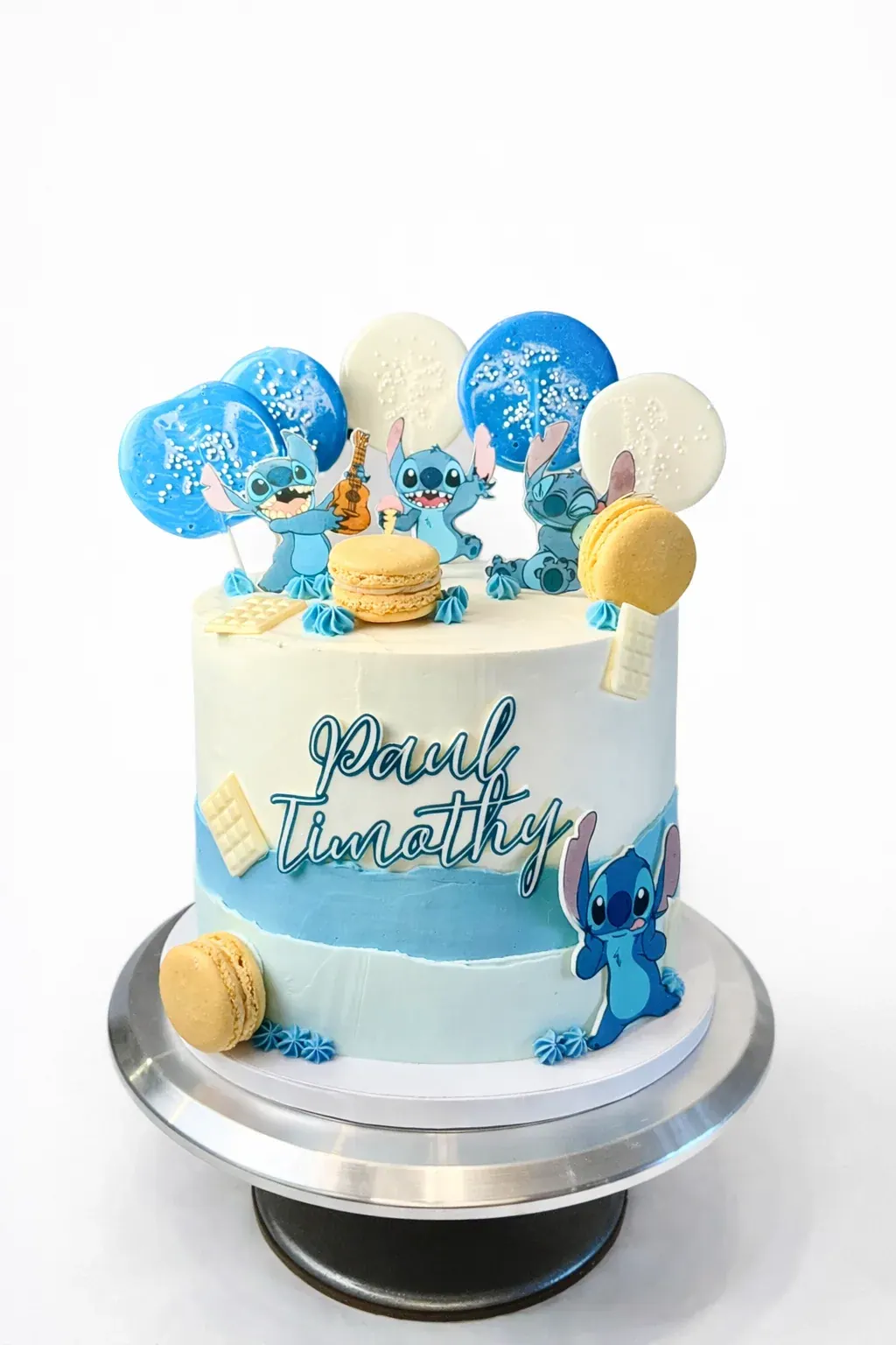 Blue and white Stitch character cake with a piped name, macarons, lollipops and Stitch figures